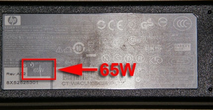 Imagen de un adaptador de CA de 65 W mostrando la ubicación de la información de potencia en vatios.
